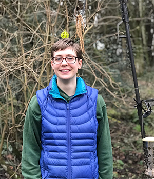 Photo of Eleanor outside in front of trees with bare bird feeders in their bare branches