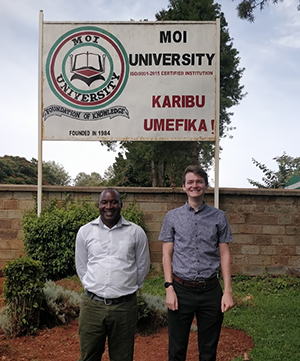 Photo of Moray Ootside the main gate of Moi University with Dr Njira Njira Pili