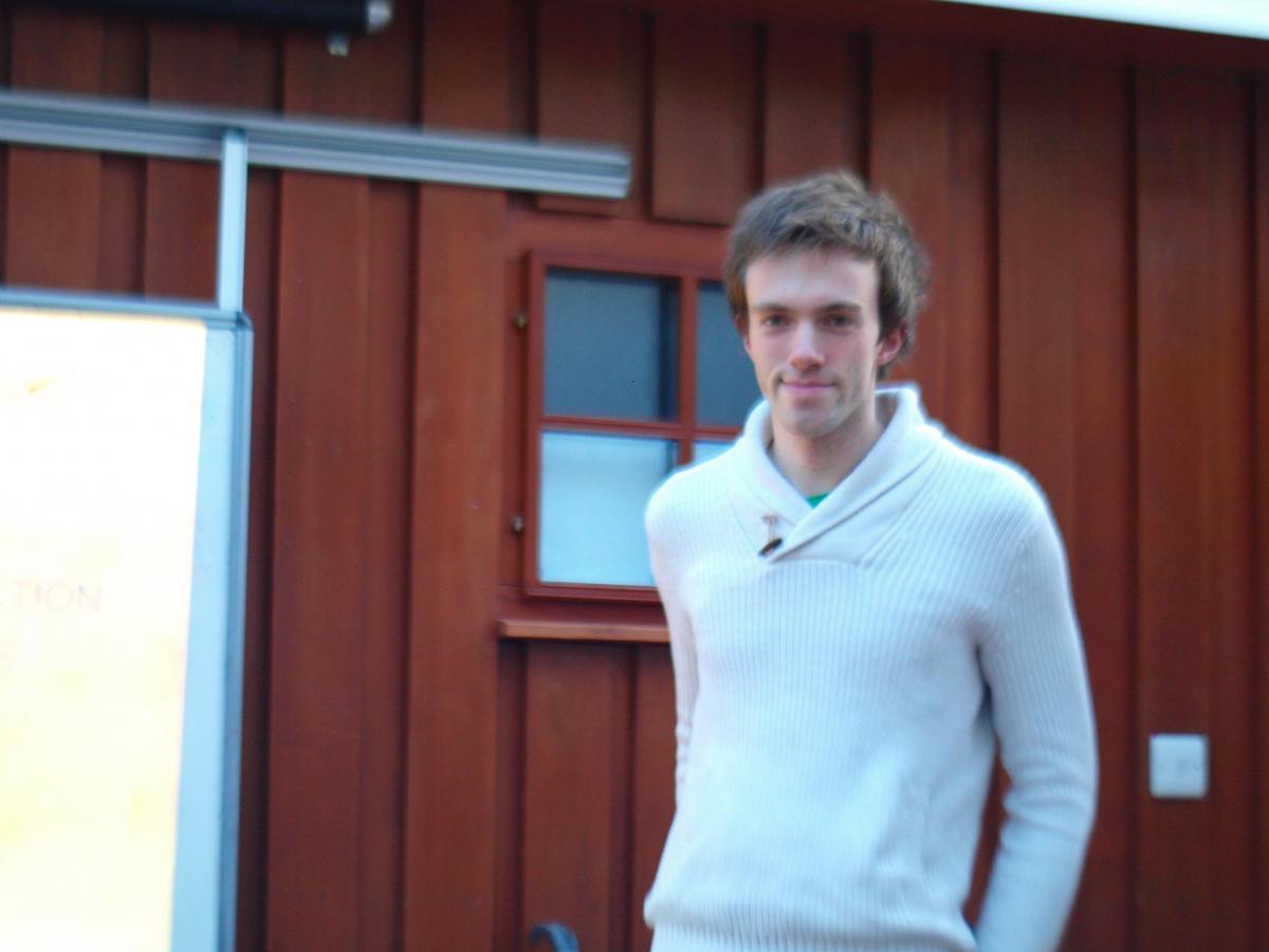 A lab member stands outside a chalet in a winter jumper