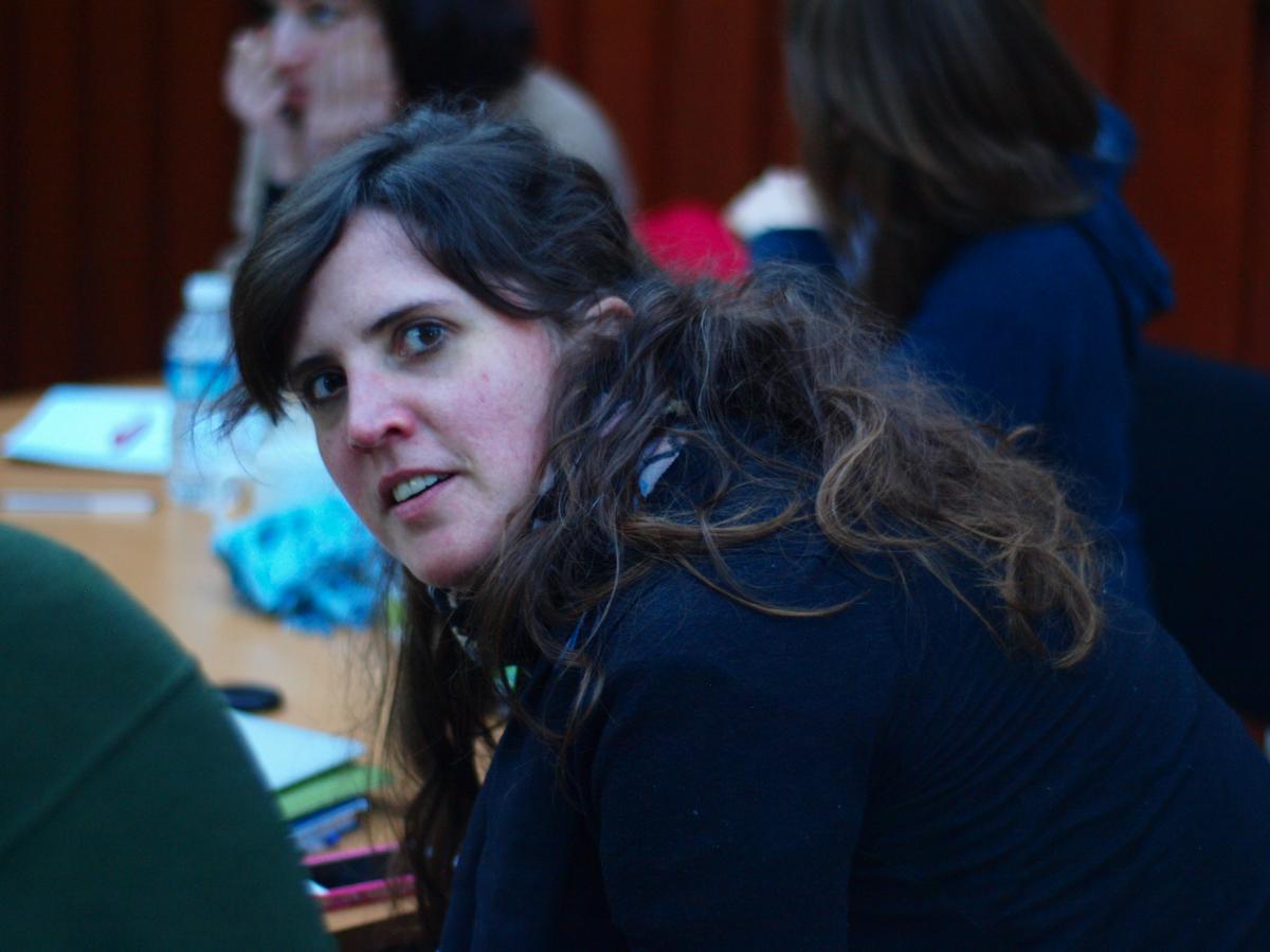 A lab member, sat at a table with other group members, turns to look at the camera