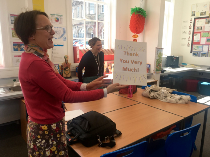 Photo of the classroom with Hilary holding a thank you card and Janice in the background