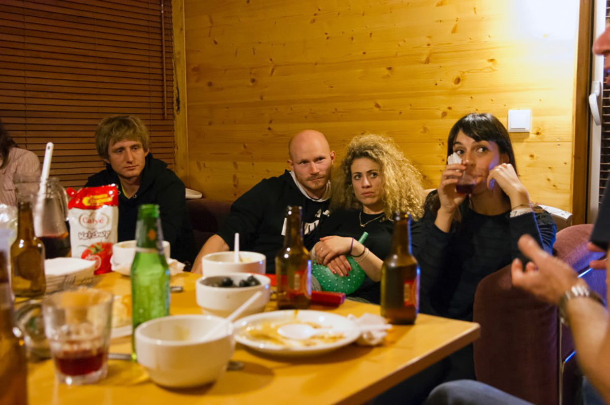 Lab group members gathered round a table, eating, drinking and chatting