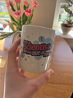 Photo of a hand holding a mug with \"I'm a scientist get me out of here\" logo on it